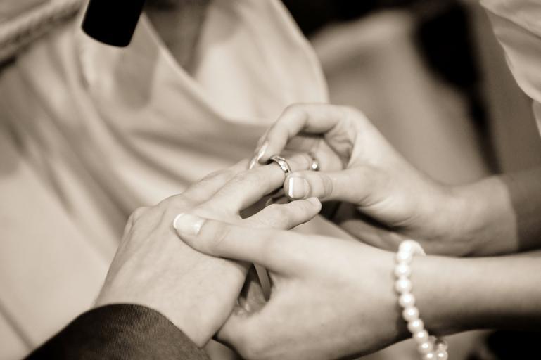 černobílá fotografie rukou, jak si předávají snubní prsteny
