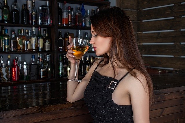 mladá žena pijící ze sklenice aperitiv v baru